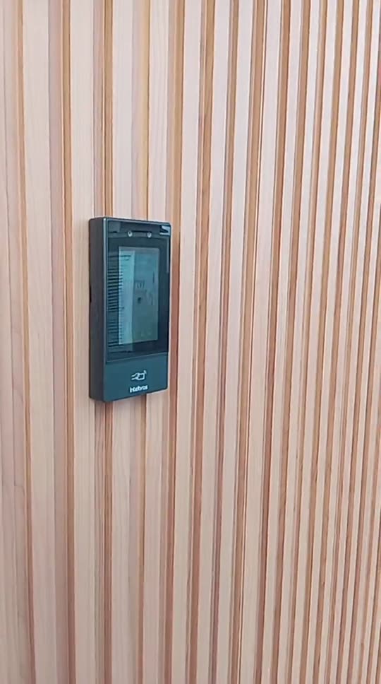 Leitor de controle de acesso facial instalado em parede de madeira